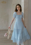 Light blue lace midi dress with square neckline and puff sleeves; tiered skirt.