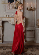 Red halter gown with open back and embellished bodice, flowing pleated skirt