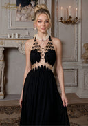 Black halter gown with beaded neckline and gold accents, long pleated skirt