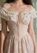 Close-up of blush off-shoulder embroidered bodice with lace ruffle neckline and bow ties