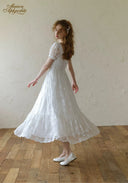 White lace dress with short puff sleeves and square neckline, gathered flared skirt.