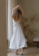 White lace midi dress with thin straps, gathered waist, flared skirt with ruffled hem