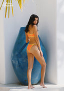 Orange bikini set in a side view with yellow-trim triangle top and matching bottoms