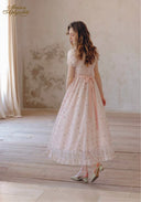 Light pink floral tea dress with puff sleeves and ribbon waist tie; standing side view.