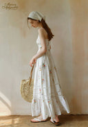 Secret Garden dress in white with floral print, tiered skirt; holding straw round bag