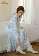 Blue floral tiered maxi dress with long sleeves and boots, seated side view.