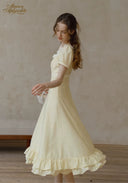 Romance dress in pale yellow with puff sleeves and tiered ruffle hem, viewed in profile
