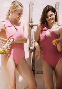 Pink one-shoulder swimsuit with rosette bow detail and high-cut bottoms