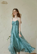 Teal satin midi dress with thin straps and ruched bust, skirt swaying view