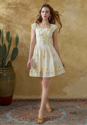 Cream linen mini dress with yellow floral embroidery, square neckline, flared skirt; cap sleeves.