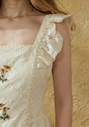 Detail of cream lace embroidered dress: ruffled cap sleeve and shoulder lace trim.