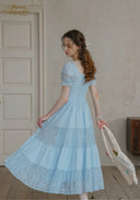 Light blue lace dress with puff sleeves and tiered skirt; square neckline.