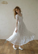 White lace midi dress with square neckline, short puff sleeves, and tiered skirt.