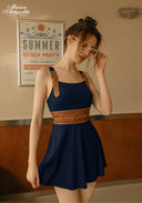 Navy swimdress with square neckline, shoulder ties, and tan braided waist belt