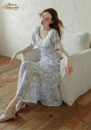 Lavender floral midi dress with puff sleeves and gathered neckline, seated angle