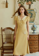 Yellow embroidered midi dress with peter pan collar, button front, and patch pockets