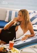 Black one-shoulder swimsuit with white cup panel and rosette detail