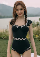 Black one-piece swimsuit with sweetheart neckline and white patterned waistband trim