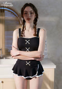 Black swimdress with front X lacing and white scalloped hem trim, sleeveless