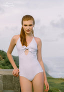 White one-piece swimsuit with bow at chest, halter straps, and sparkle dot pattern.