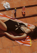 Green cut-out one-piece swimsuit with halter straps and oval bust cut-out, lying down