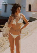 White bikini set with triangle top and tie side briefs, hands on hips