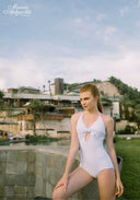 White one-piece swimsuit with halter neckline, bow detail, and sparkle dot pattern.