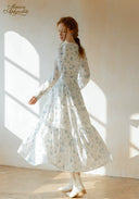 Blue floral tiered maxi dress with long sleeves and ruffled hem, side view.