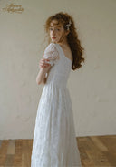 White lace dress with square neckline and puff sleeves, cinched waist and full skirt.