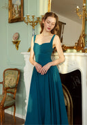 Teal blue suspender dress with square neckline, spaghetti straps, and pleated skirt detail.