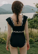 Black one-piece swimsuit with open back and white patterned panels, rear view