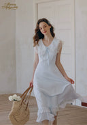 White V-neck lace midi dress with cap sleeves and tiered ruffle hem, seated pose