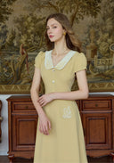 Yellow embroidered dress with peter pan collar and button front, chest and pocket motifs