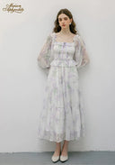 Woman wearing a floral dress with sheer sleeves against a white background