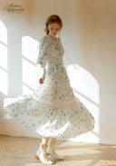 Blue floral tiered maxi dress with long sleeves and flared ruffle skirt, angled view.