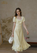 Romance dress in pale yellow with short puff sleeves and ruffled hem, holding white basket bag