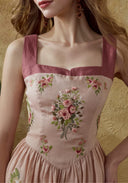 Close-up of pink linen maxi dress bodice with burgundy trim and floral embroidery