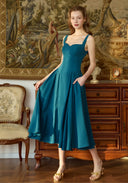 Teal blue suspender dress with square neckline, sleeveless bodice, and flared pleated skirt.