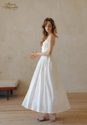 White midi dress with thin straps, lace bodice, and full flared skirt
