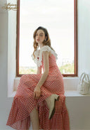 Front view of gingham plaid maxi dress with off-shoulder lace trim and red bow accents