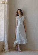 White lace V-neck midi dress with ruffled shoulders and skirt, standing pose