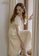 Lace tea dress in pale yellow with V-neck lace bodice and puff sleeves, sitting pose