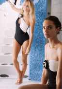Black one-piece swimsuit with white sweetheart bust panel and rose accent