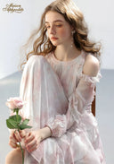 Floral tiered dress in pale pink with ruffled neckline, close-up while holding a rose