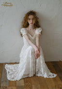 White lace midi dress with square neckline and puff sleeves, flared skirt and lace trim.