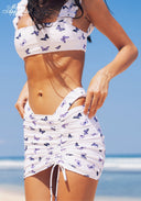 Three-piece bikini set close-up: lilac butterfly print triangle top and ruched tie mini skirt.