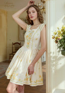 Cream linen dress with yellow floral embroidery and square neckline, gathered skirt detail.