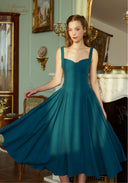 Teal blue suspender dress with square neckline and wide pleated skirt, close front angle.