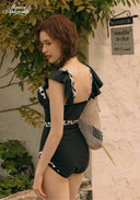 Black one-piece swimsuit with ruffled sleeves and white patterned back panels, rear view