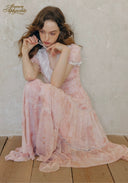 Rose pink lace-trimmed dress with short sleeves, bowlike neckline detail, seated
